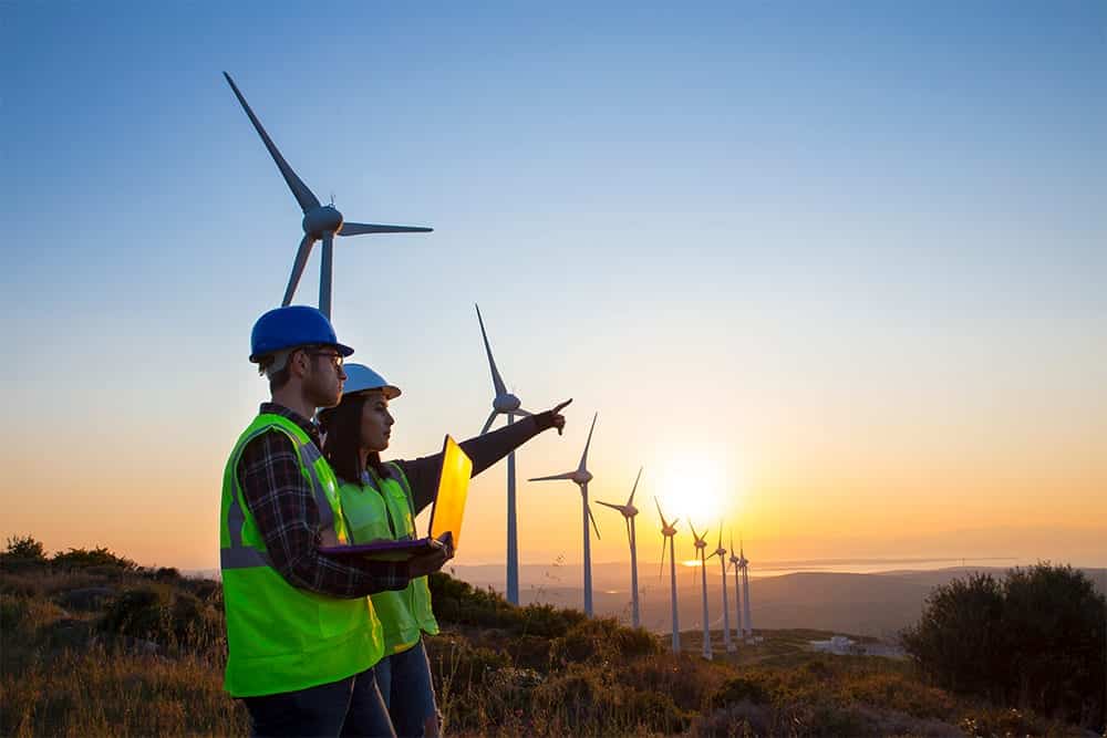 Two energy workers standing in front of wind mills, asset navigation for energy