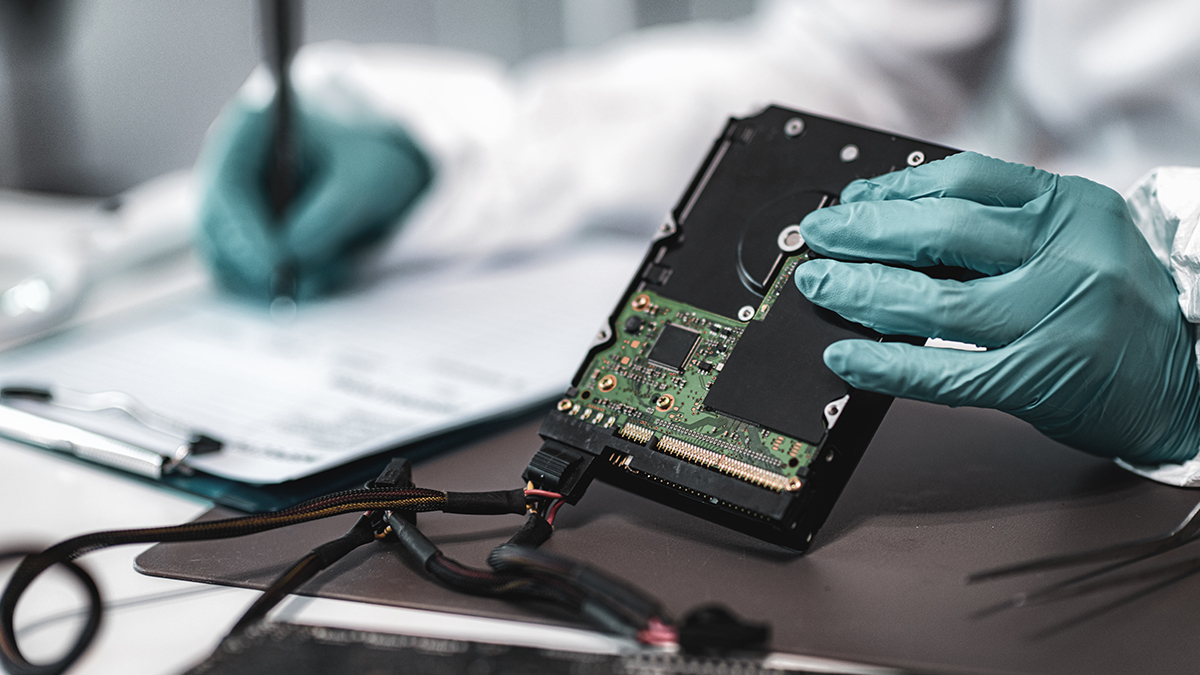 A forensic investigator examines a computer hard drive. 