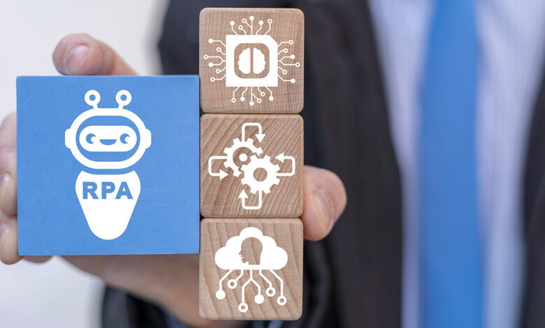 Close-up on wooden blocks with gears and a robot with the letters RPA for Robotic Process Automation.