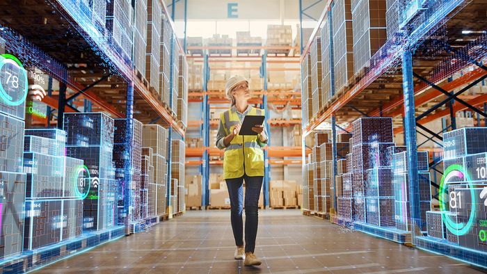 This is an image of a woman holding a tablet in a supply chain warehouse.