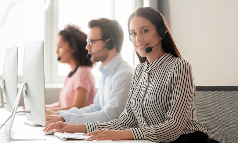A group of contact center agents with headsets on work in front of computers.