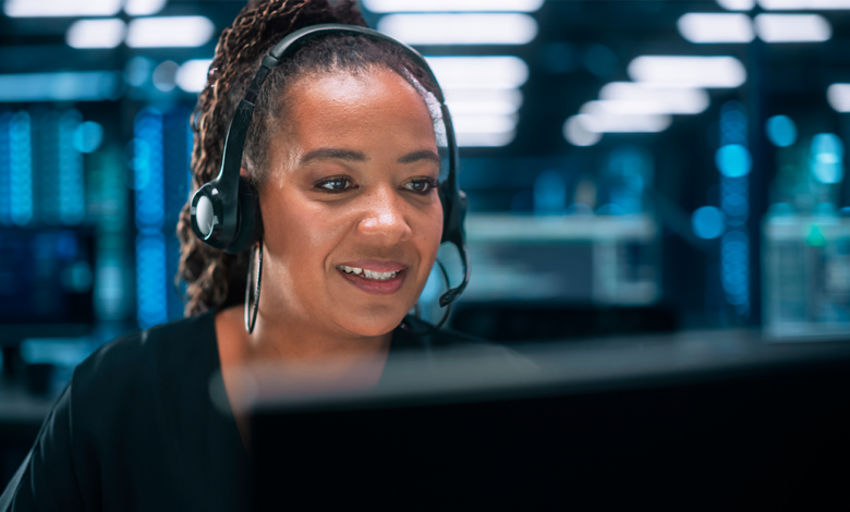 A female agent with a head-set on takes a customer call at a computer work station.