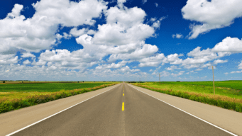 An image of an open road with clouds above.