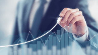 A business person holding a pen draws a linear illustration of growth as a bar graph.