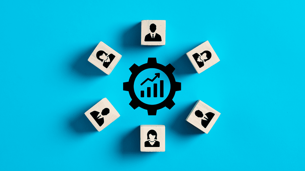 Wooden blocks layed in a circle with symbols of people and a graph with an upward trend to illustrate employee productivity.