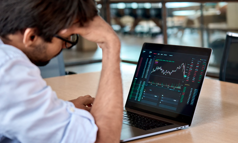 Male professional looking at graphs on a laptop to analyze economic recession.