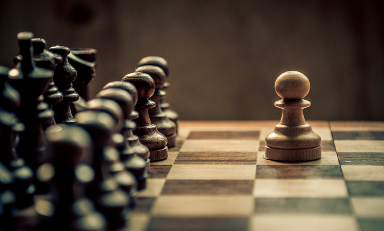 A close up of a chessboard with one white pawn facing the all of the black pieces, symbolizing how digital transformation is like a chess match