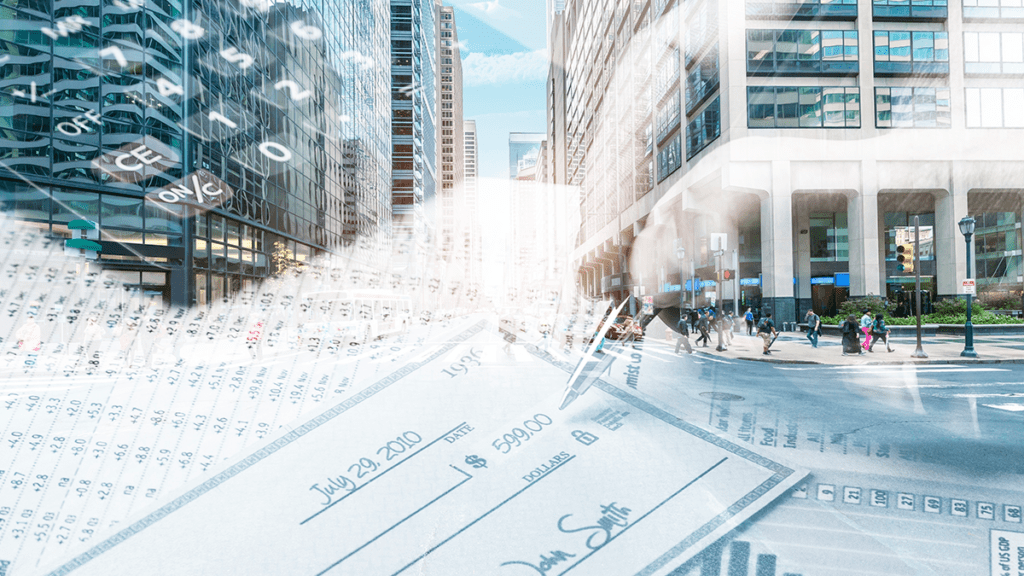 This is an image representing accounts payable automation with a hand, writing a cheque next to a computer screen.