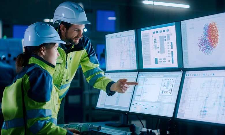 This is an image of two people in hardhats looking at multiple computer screens and enjoying the benefits of cloud-based supply chain integration..