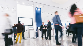 image of a trade show floor, blurred people walking past and holding conversations