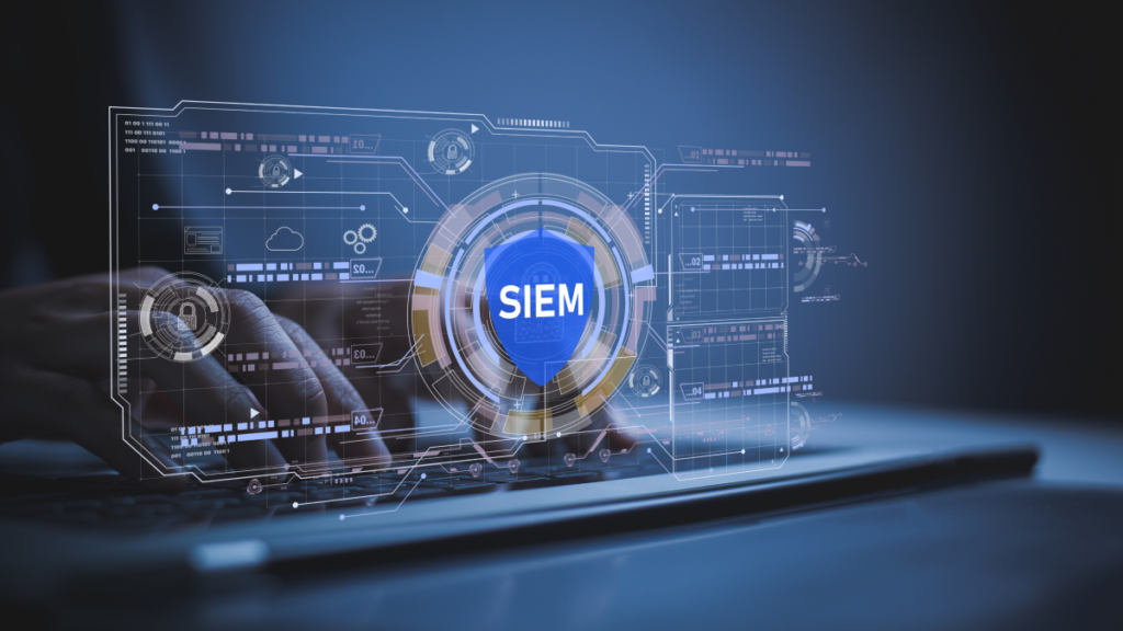 Fingers typing on a keyboard. In front of the keyboard, a transparent screen shows a computer interface. In the middle, there is a orange tinted circle with a blue shield in the middle. In the middle of the shield, it says SIEM. The whole image has a blue tint to it.