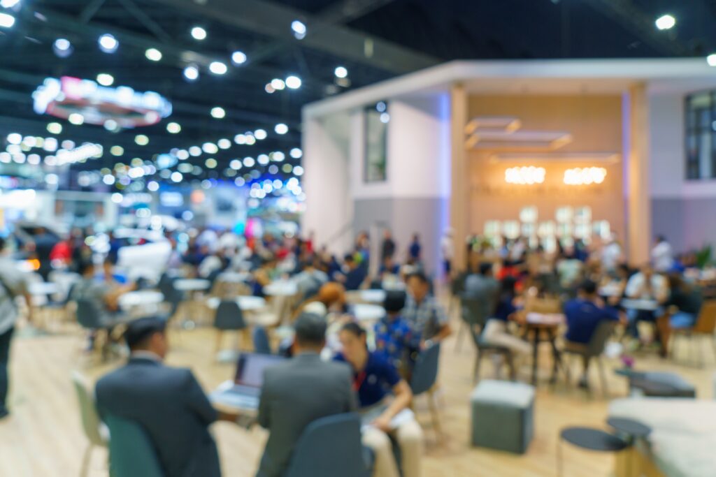 an unfocused view of a large group of people milling around inside a room