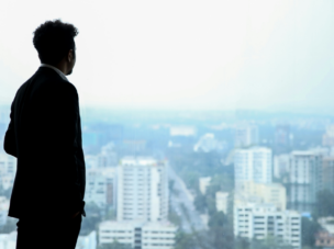 Man looking out a window at a cityscape