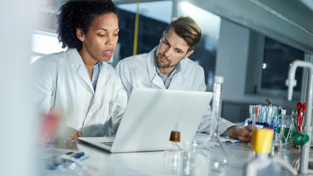 Two scientists in a lab looking at a laptop screen
