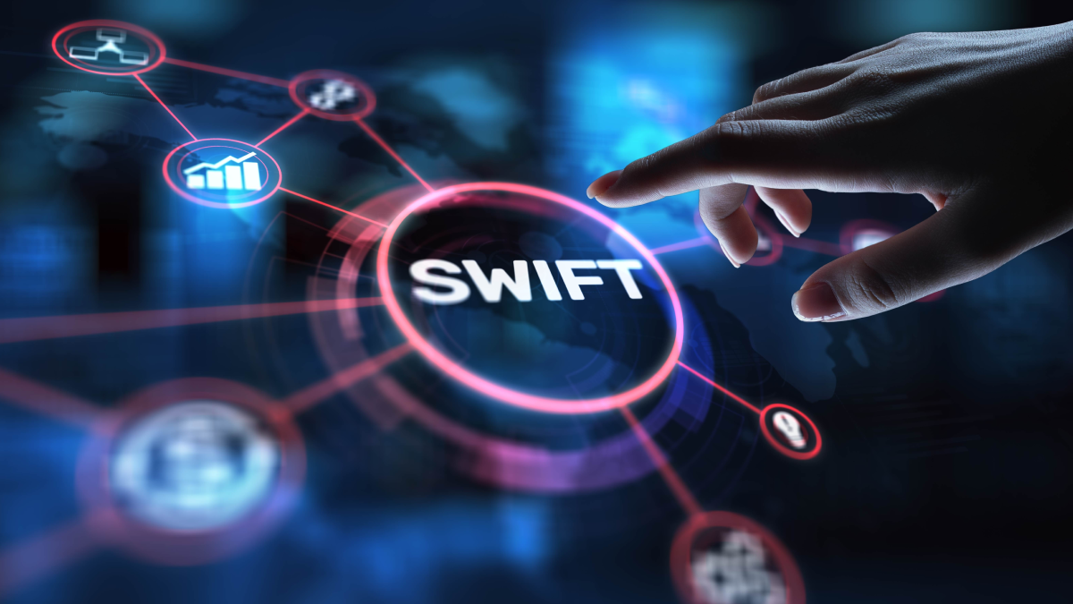 dark background with round button that reads SWIFT; worker is pointing to it about to start ISO 20022 bank modernization