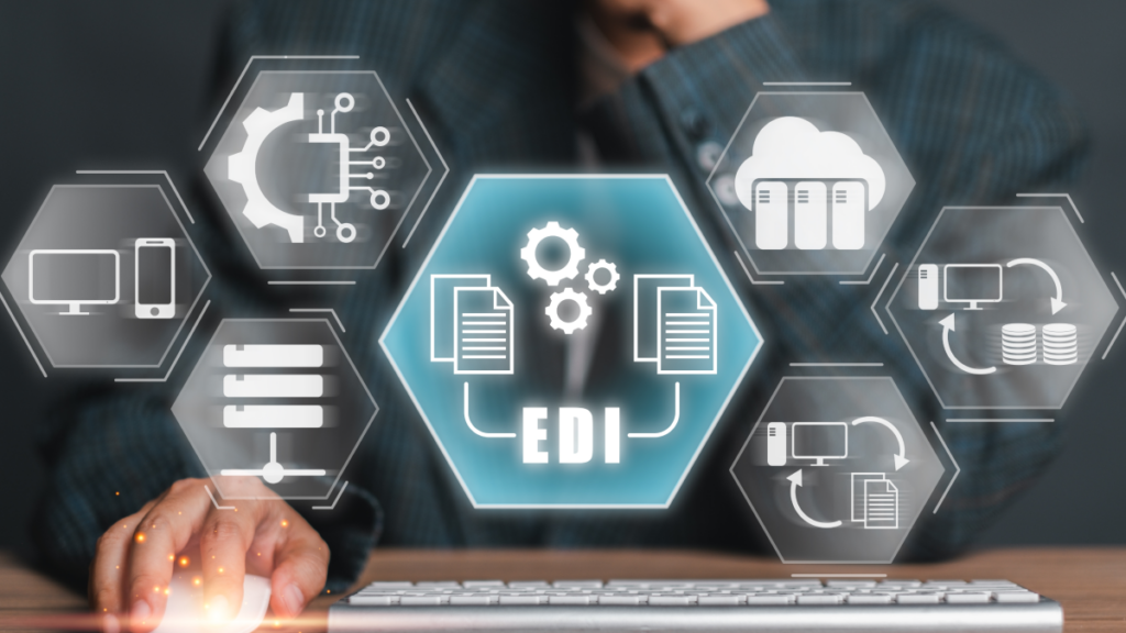 worker at desk with laptop with his hand on the mouse; EDI icons float in shot over keyboard,, showing B2B integration and EDI supply chain excellence.