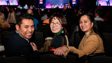 Three smiling people in the crowd of a technology conference