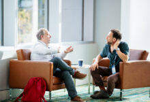 Two businessmen sitting in chairs having a conversation at a conference