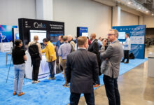 Two businessmen having a conversation in front of a booth at a trade show