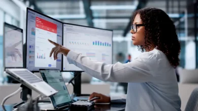 female employee working at two monitors, looking at treasury infrastructure and operations dashboards